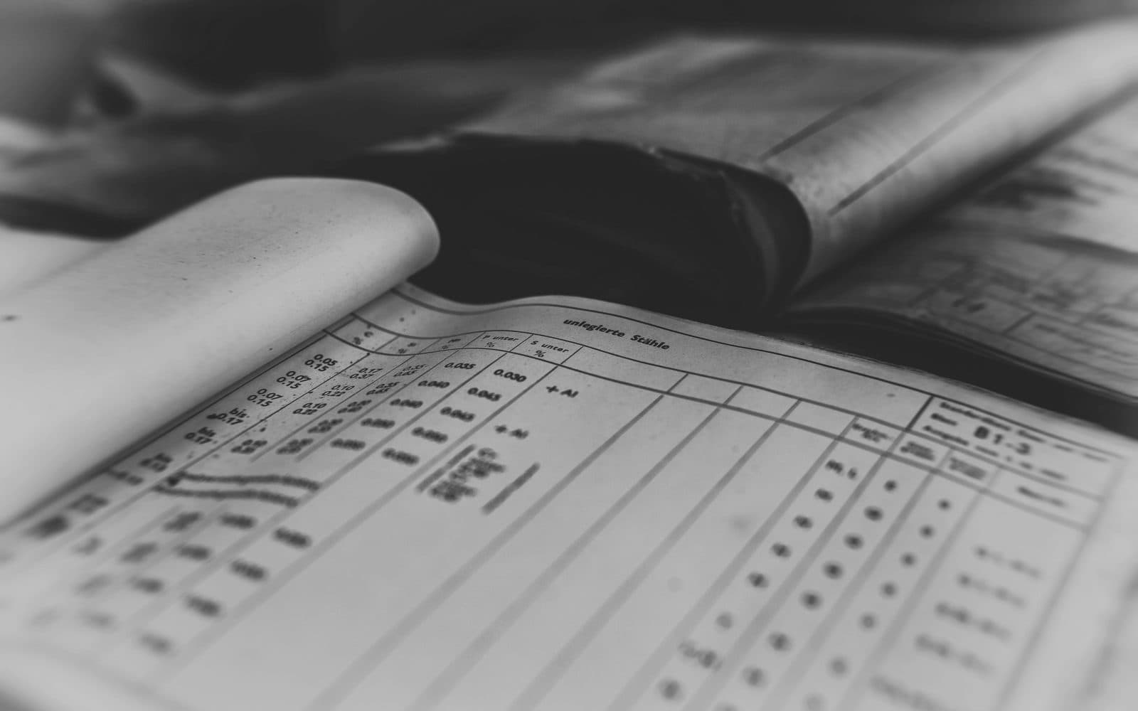Commercial shipping documents and a bill of lading laid out beside a laptop